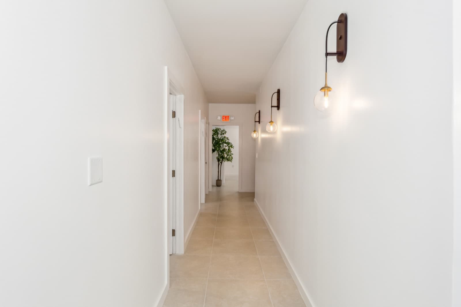 The hallway at Ora, lit by a run of glass globe sconces