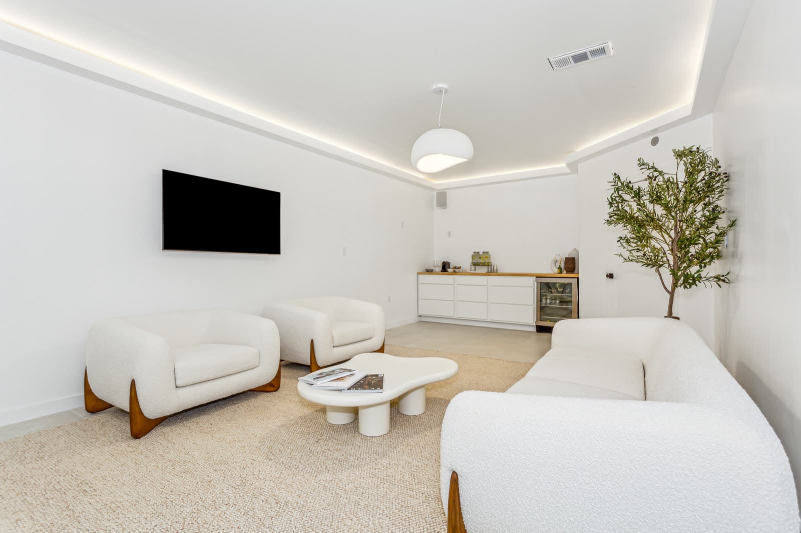 The lounge at Ora — boucle chairs and a sofa around a low table, under a cove-lit ceiling